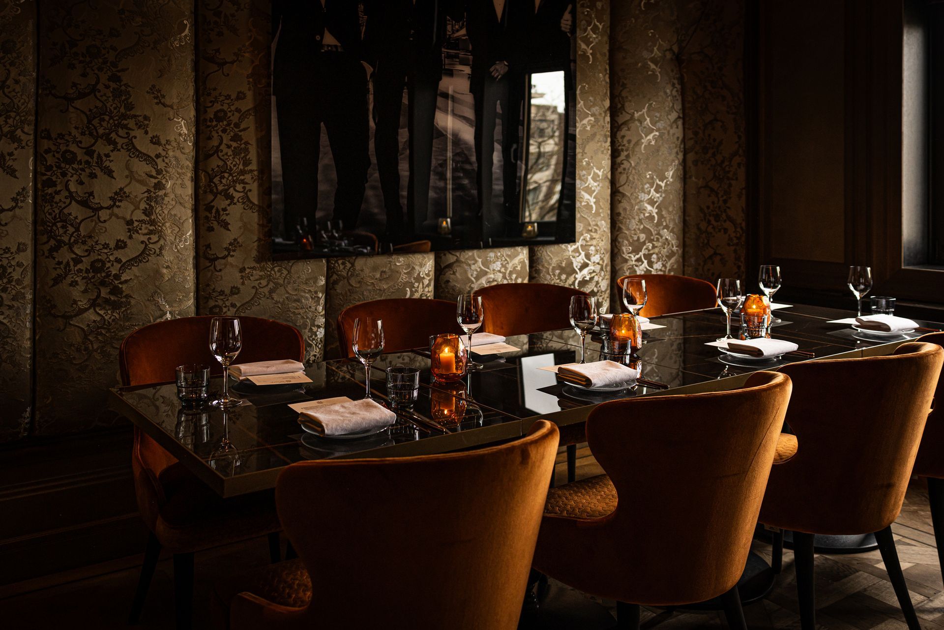 Elegant restaurant dining room with set tables, leather chairs, and warm candlelight