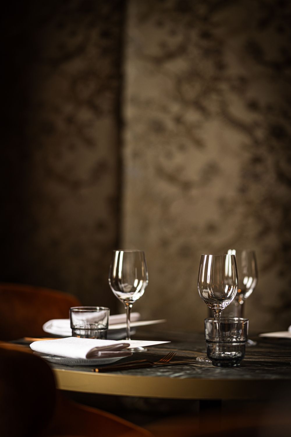 Set dining table with wine glasses and plates in a dimly lit restaurant