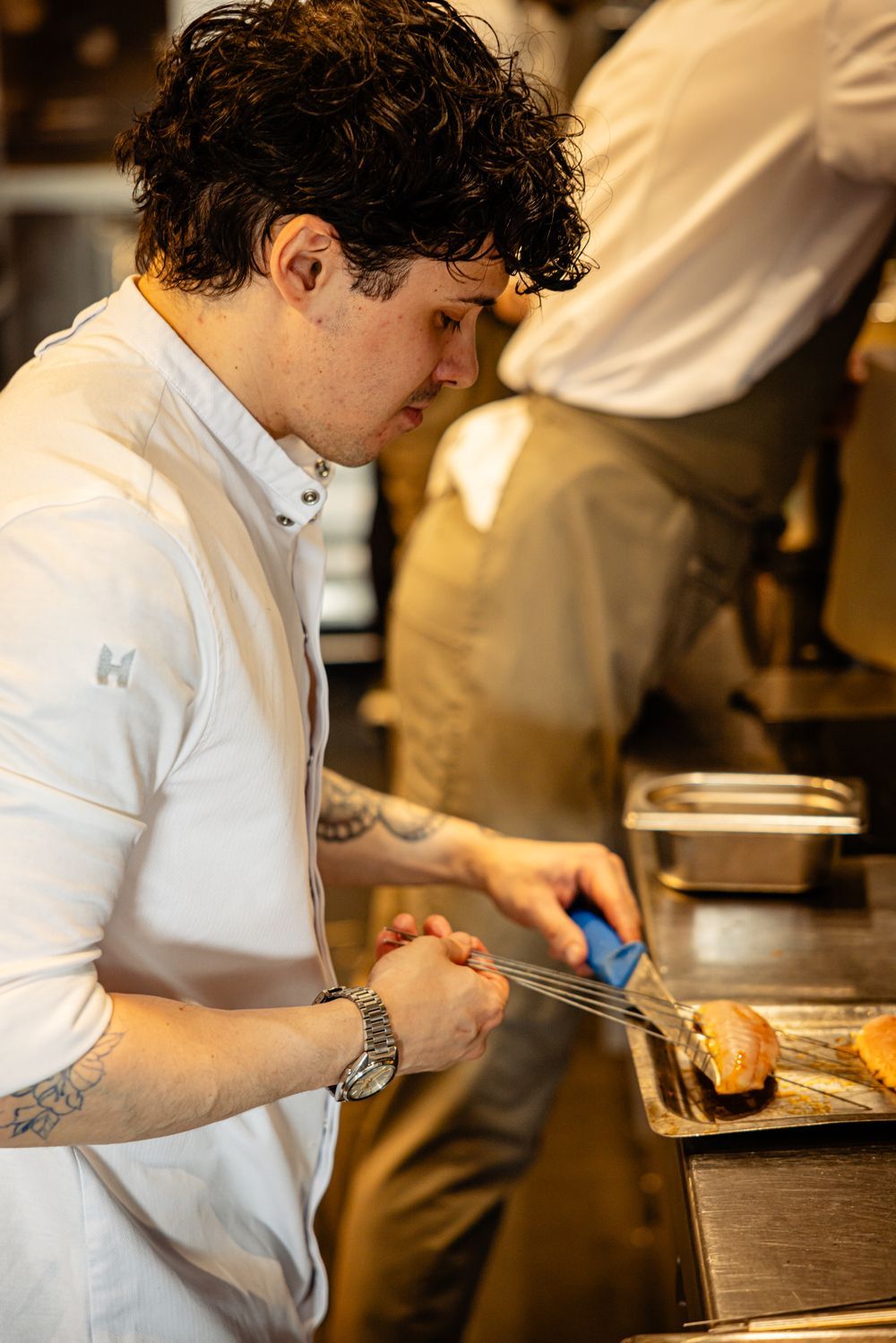 Chef plating food at a stainless-steel counter in a restaurant kitchen