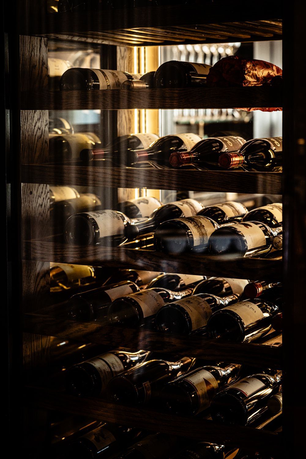 Wine bottles stored on wooden shelves in a dimly lit wine cellar