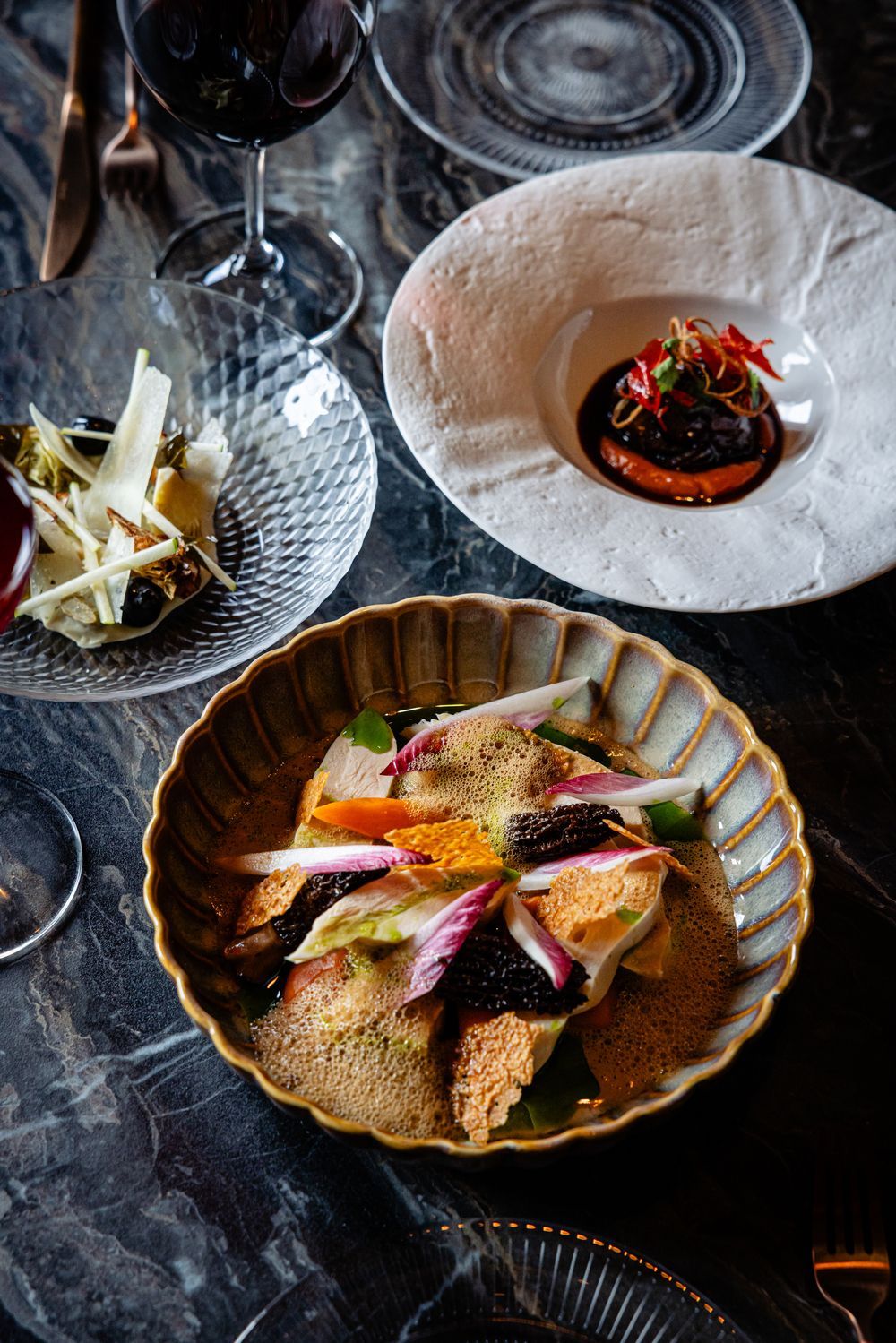 Gourmet plated dishes with colorful garnishes on a dark restaurant table