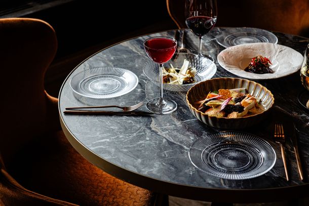 Elegant dining table set with wine glasses, plates, and plated food in a dimly lit restaurant