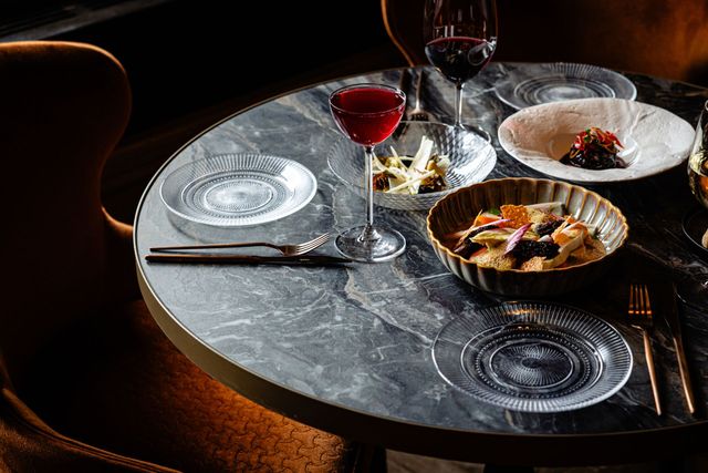 Elegant dining table set with wine glasses, plates, and plated food in a dimly lit restaurant