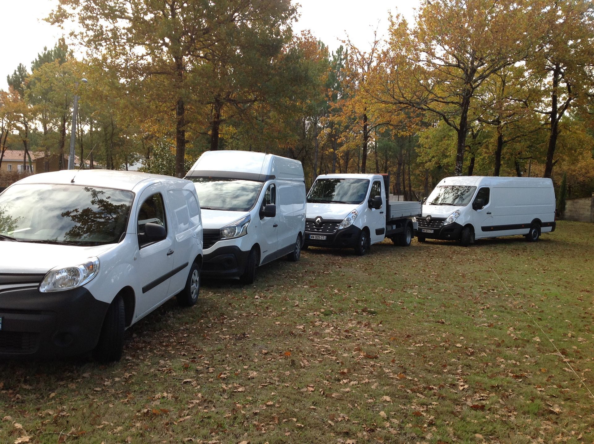 Camionnettes, fourgons et camion-bennes blancs les uns derrière les autres