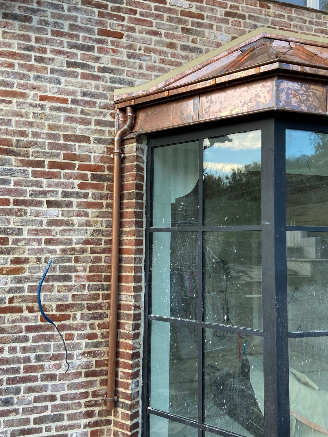 Toiture en cuivre avec une descente de gouttière en cuivre le long d'une fenêtre