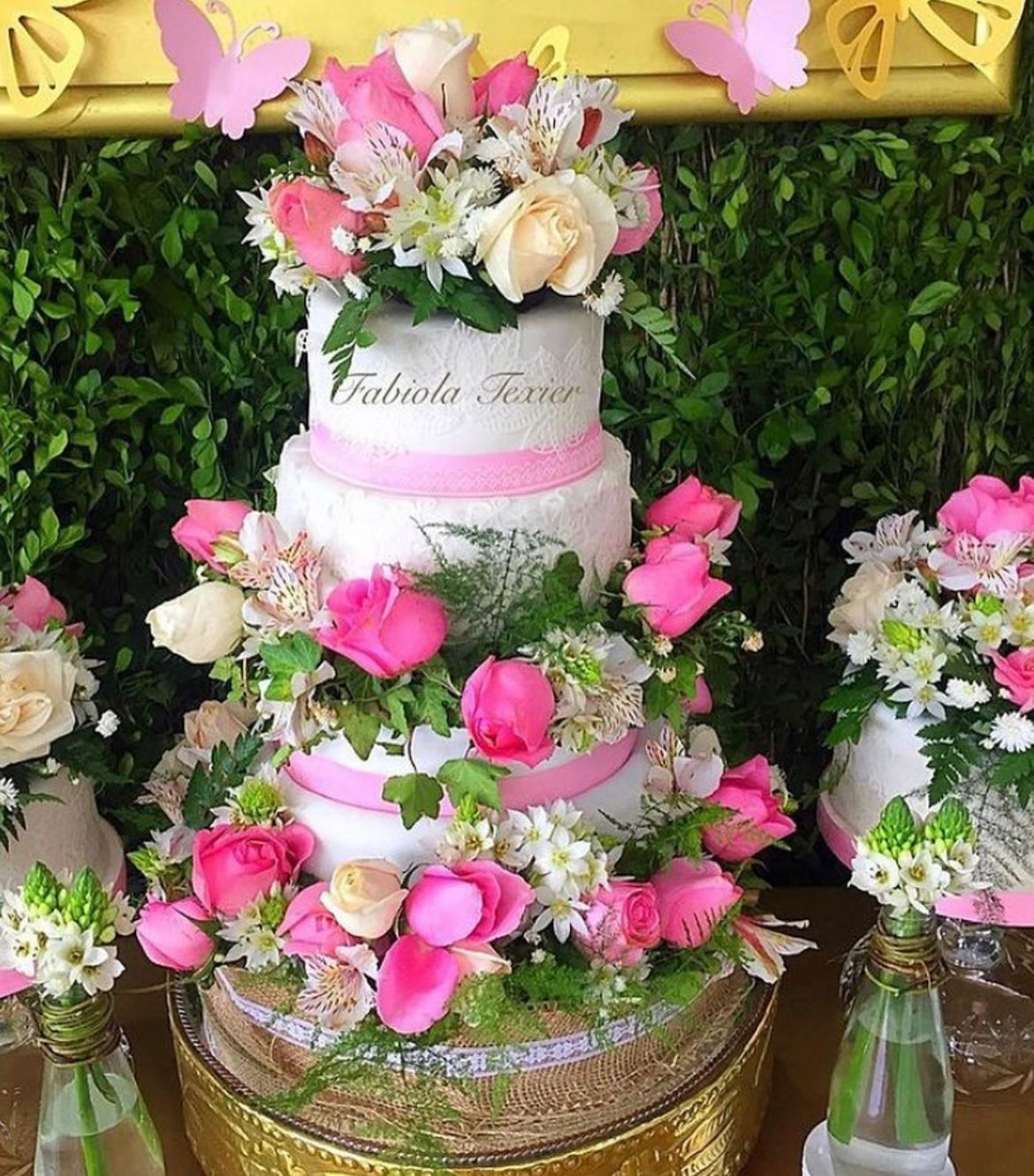 Un pastel de bodas decorado con flores rosas y blancas está sobre una mesa.