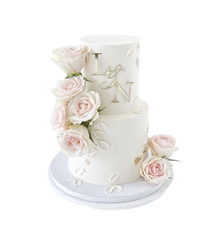 Un pastel de bodas blanco con rosas rosadas y monogramas.
