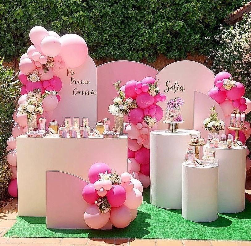 Una mesa con globos rosas y flores encima.