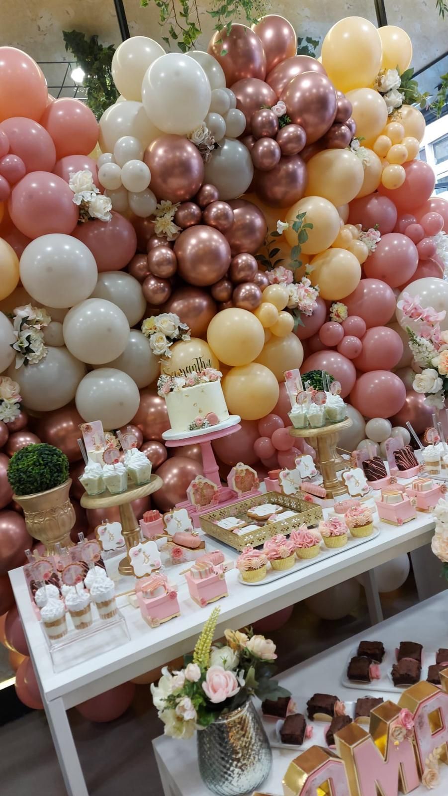 Una mesa cubierta con cupcakes y globos para una fiesta de cumpleaños.