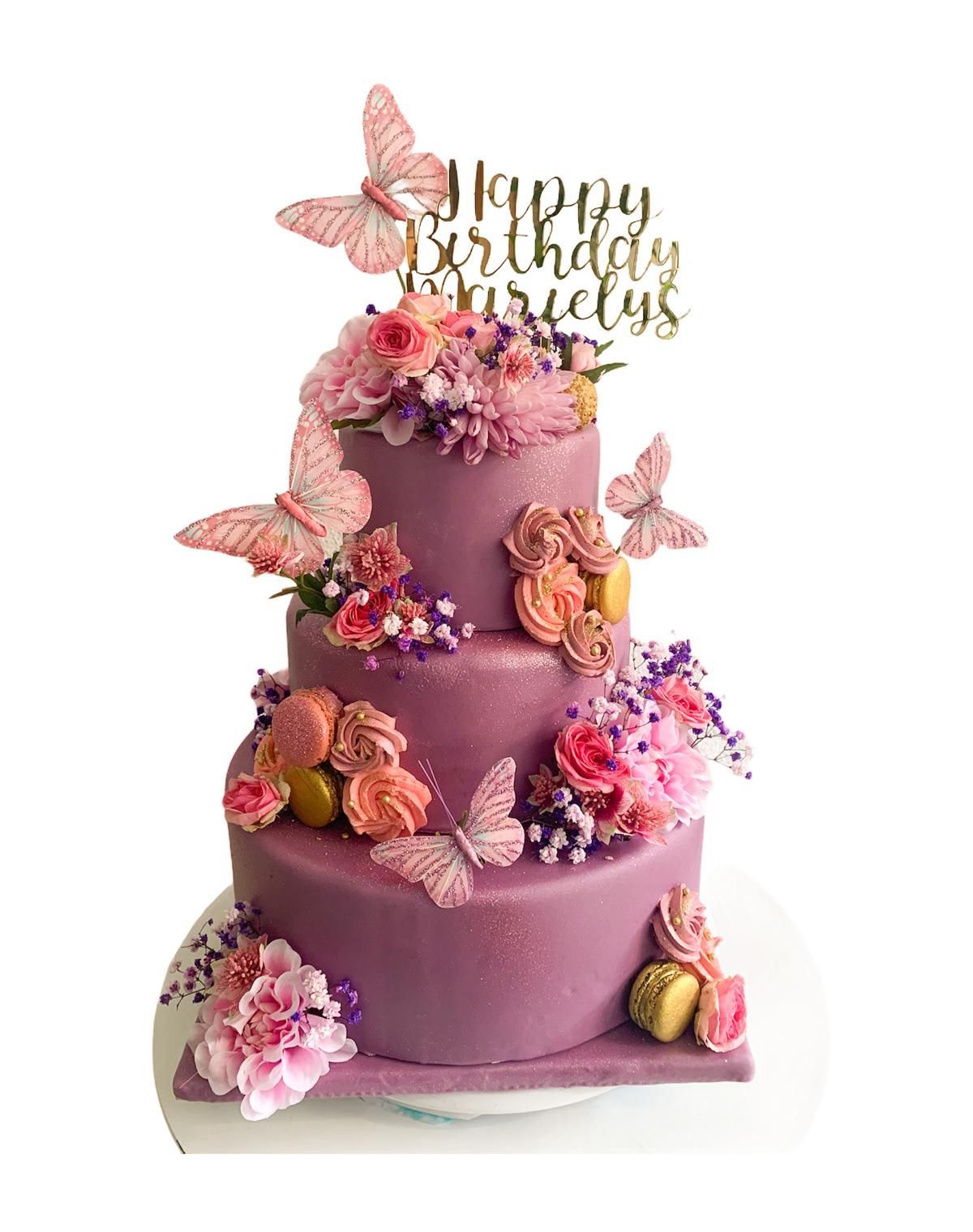 Un pastel de cumpleaños morado con mariposas y flores.