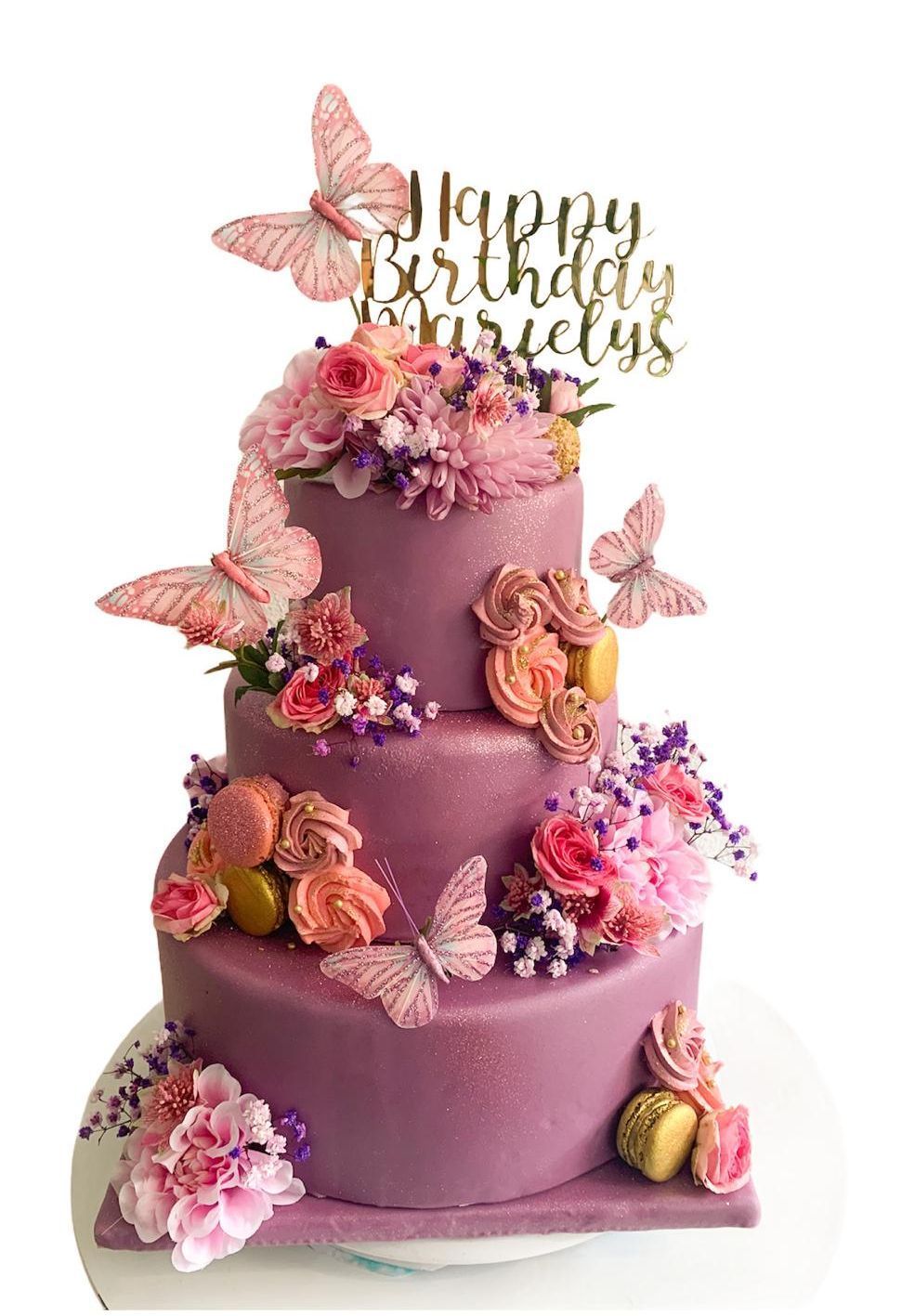 Un pastel de cumpleaños morado con mariposas y flores.