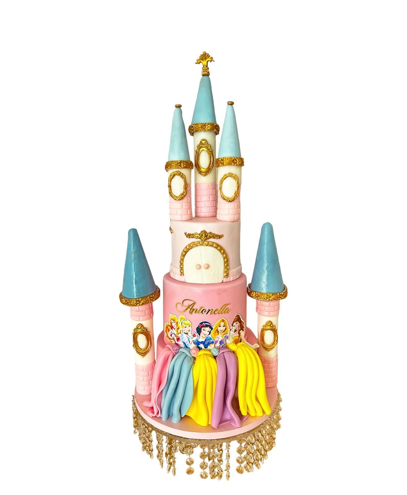 Un pastel en forma de castillo con princesas encima.