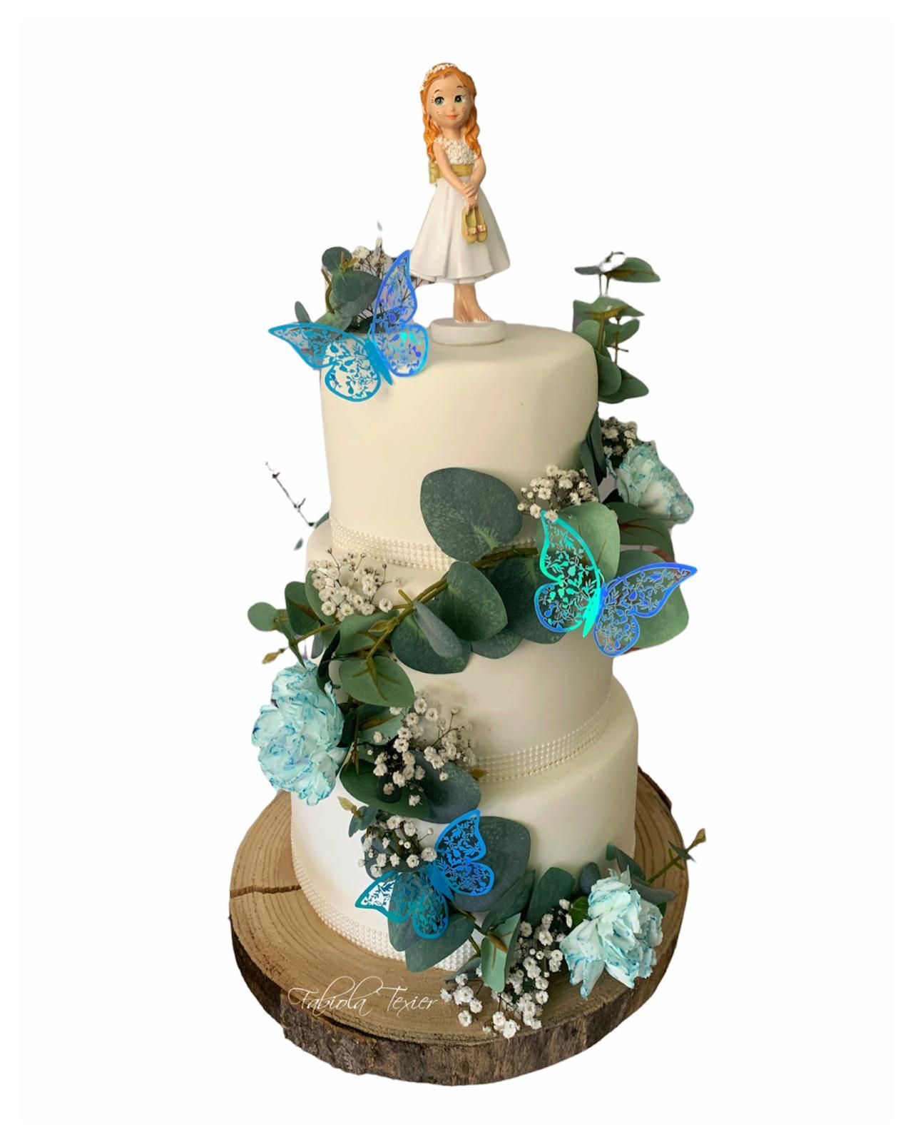 Un pastel de tres niveles con una figura de una niña encima.