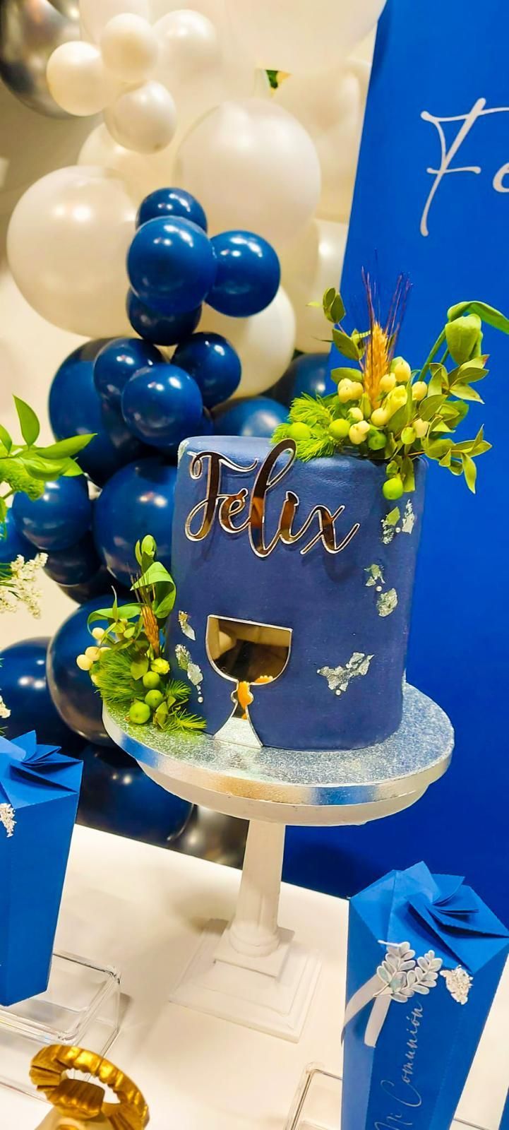 Un pastel azul con el nombre Félix está sobre una mesa.