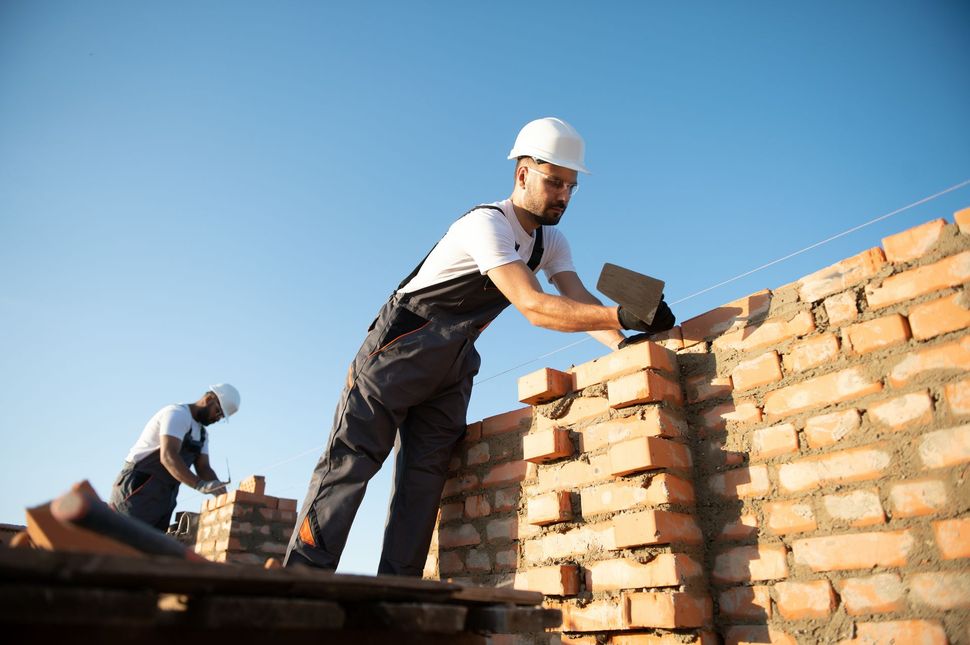 A white van is parked in front of a building under construction.