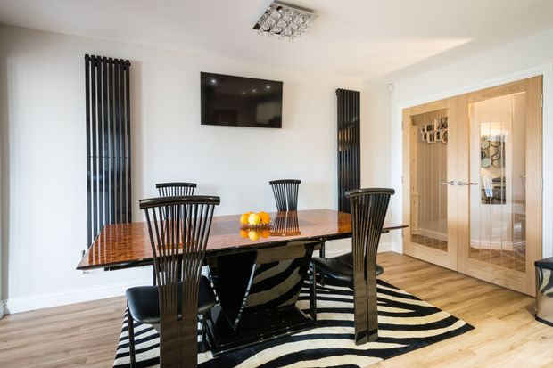 A dining room with a table and chairs and a zebra print rug.