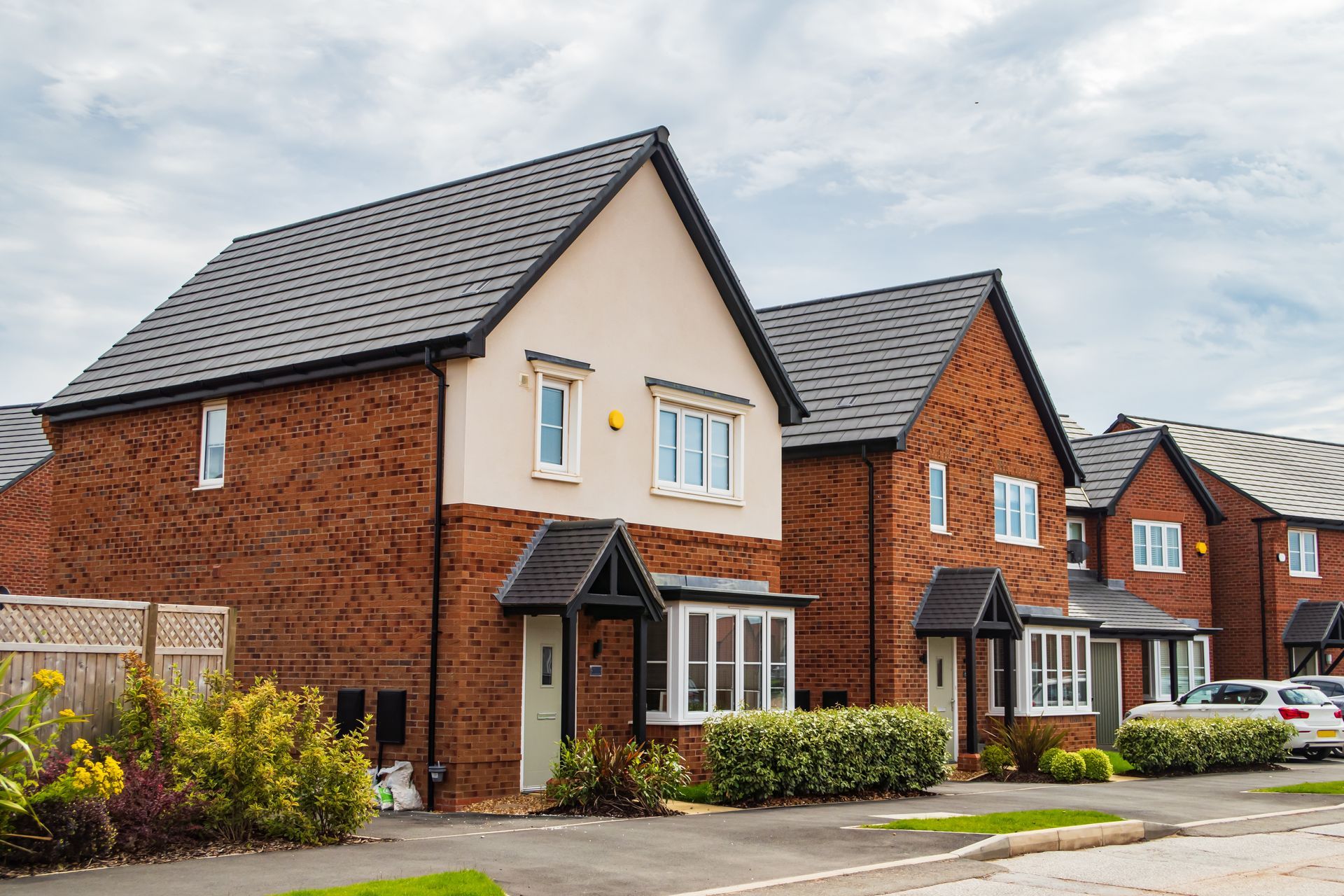 A row of brick houses in a residential area with cars parked in front of them.