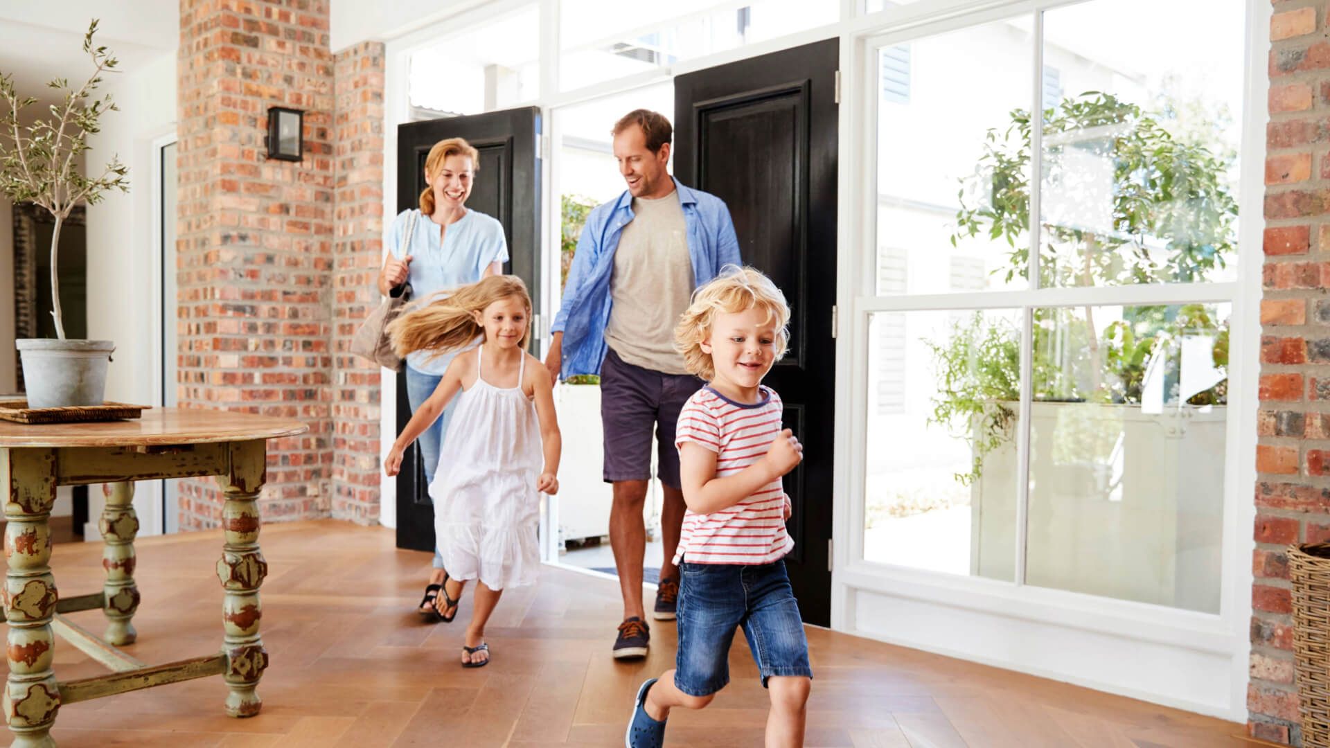 A family is walking through a living room holding hands.