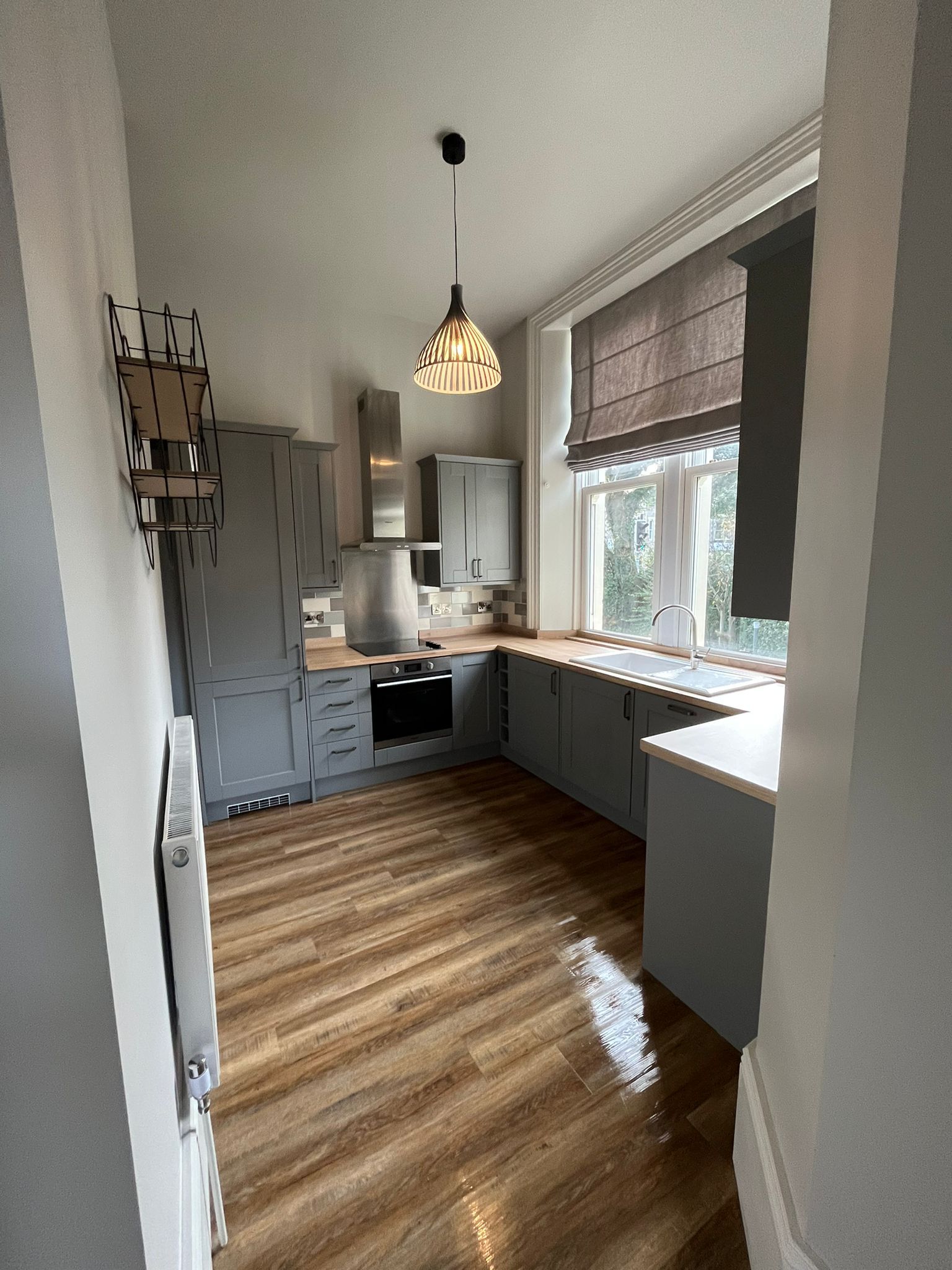 A kitchen with gray cabinets and wooden floors