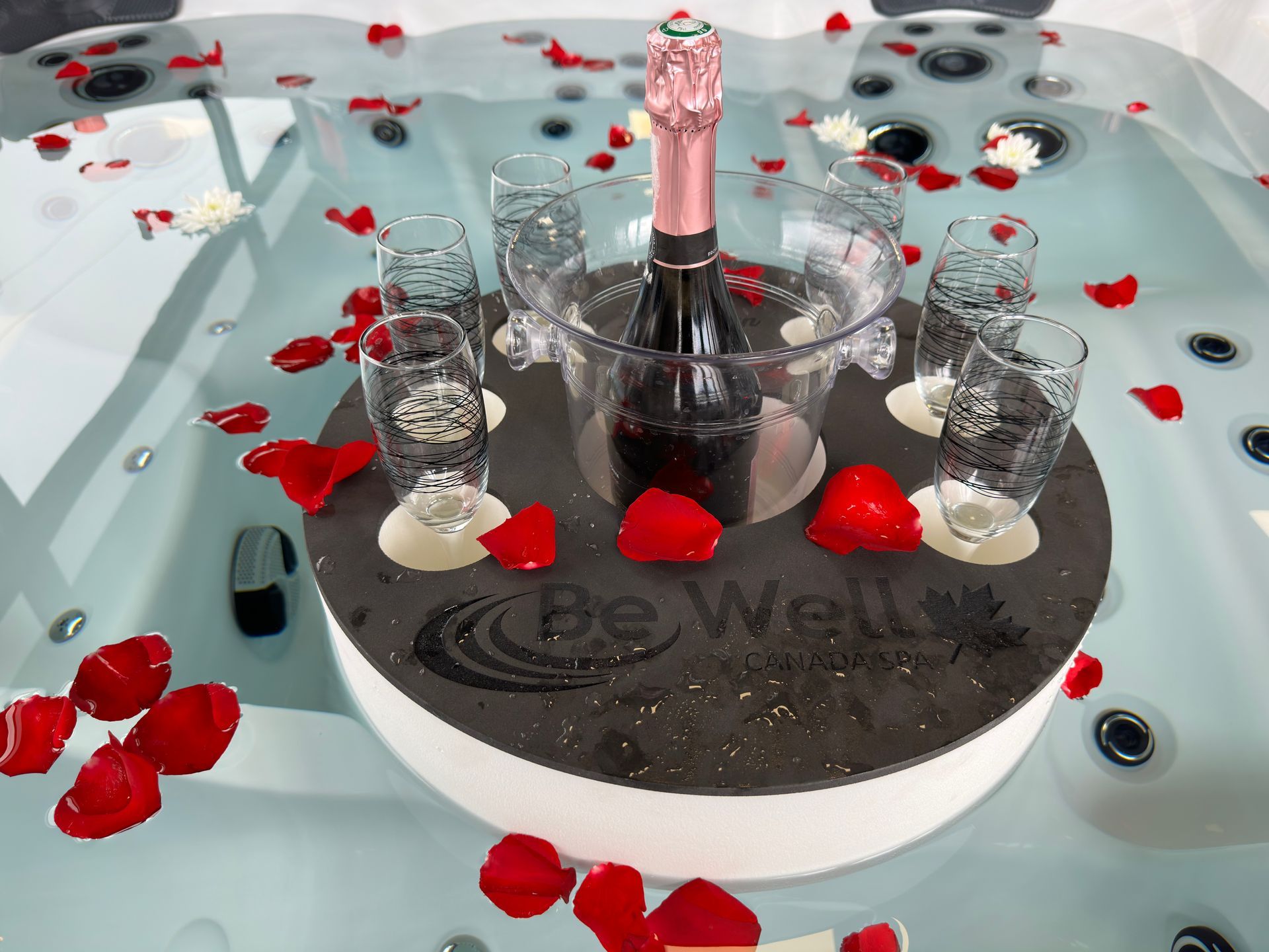 Bain à remous avec champagne, verres et pétales de rose pour une célébration romantique.