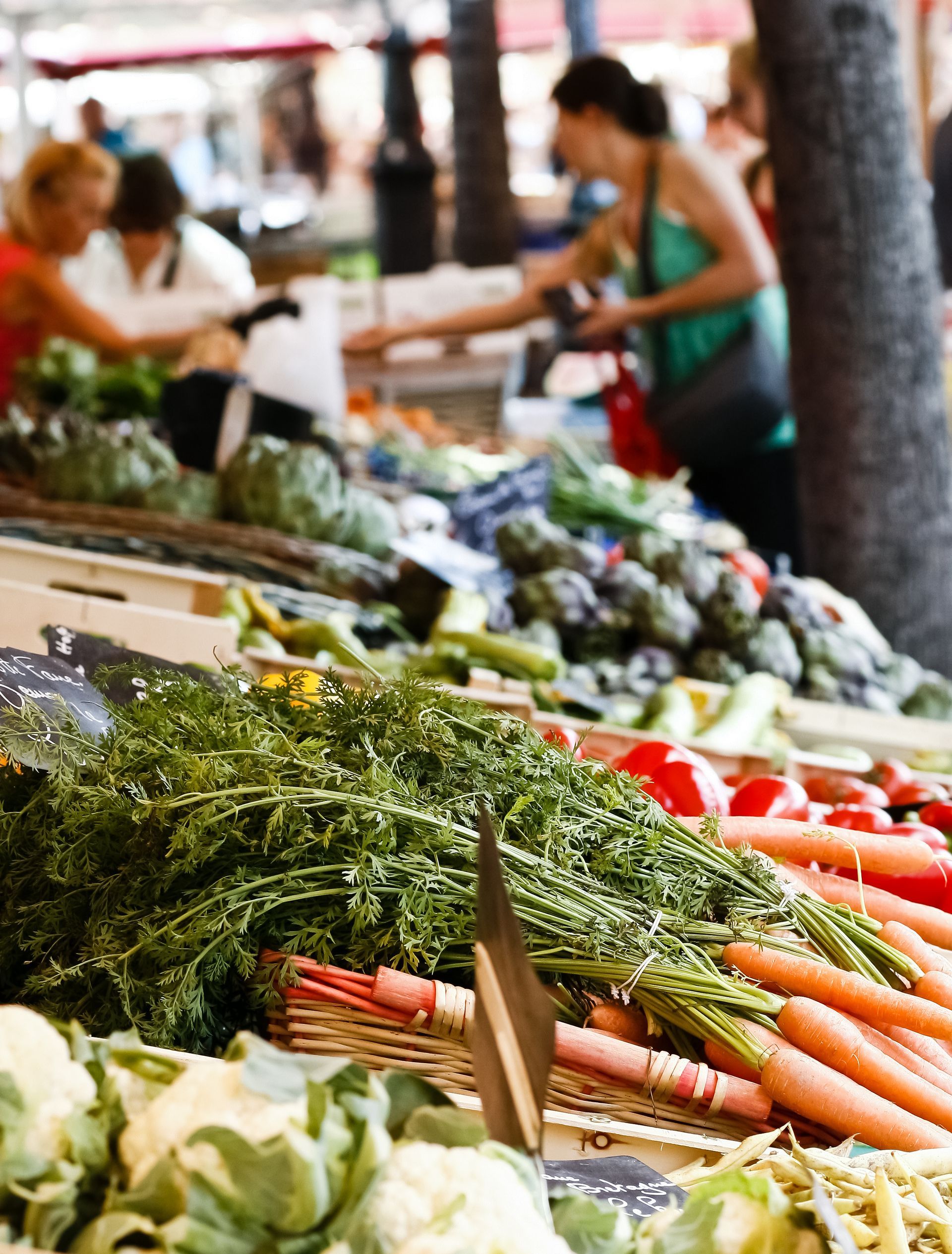 Des produits frais sur un marché de producteurs, avec des gens qui naviguent et achètent.