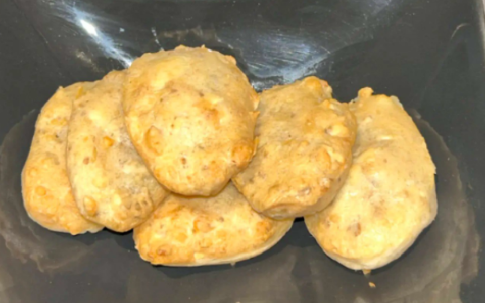 Pile de madeleines dorées sur une surface sombre.