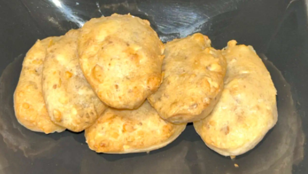 Six madeleines dorées sur une assiette sombre.