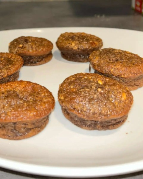 Six petits produits de boulangerie ronds sur une assiette blanche ; ils ont une garniture brune et texturée.