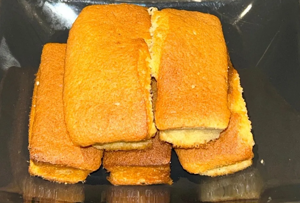 Pile de pâtisseries rectangulaires dorées dans un récipient foncé.