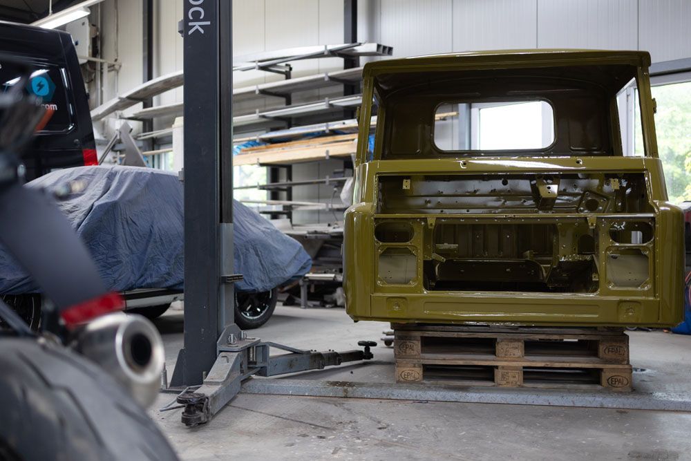 Ein grünes Auto steht auf einer Palette in einer Garage.