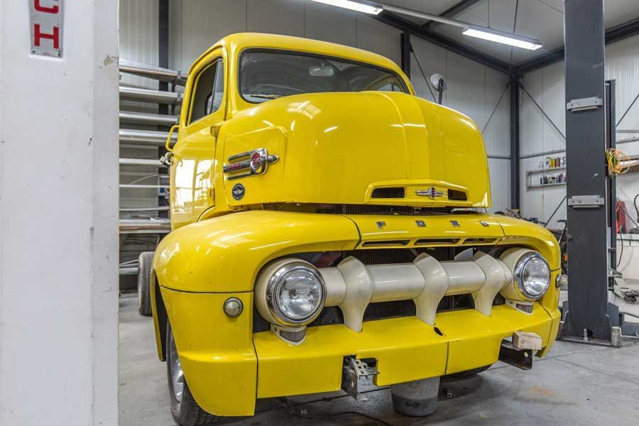 Ein alter gelber Lastwagen steht in einer Garage.
