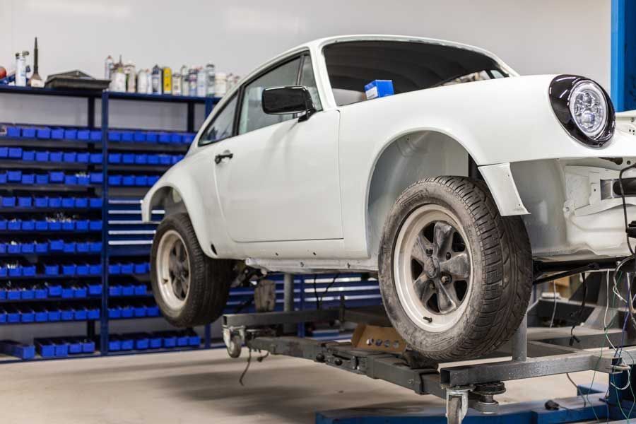 Ein weißes Auto steht auf einer Hebebühne in einer Garage.