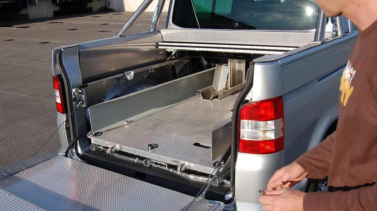 Ein Mann arbeitet auf der Ladefläche eines silbernen Lastwagens