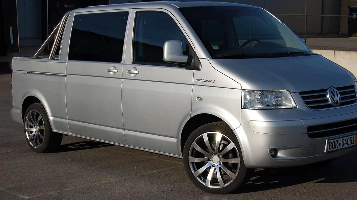 Ein silberner Van mit einer Ladefläche steht auf einem Parkplatz