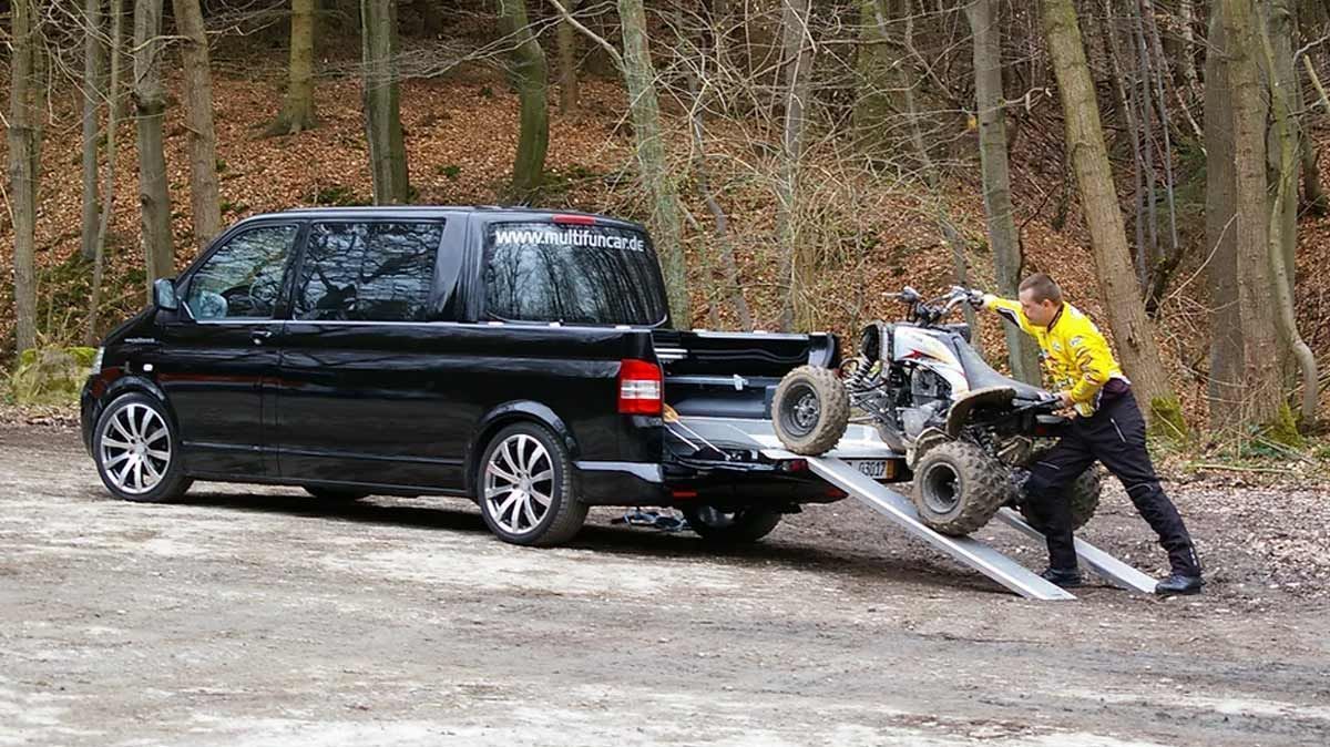 Ein Mann schleppt auf einer Rampe ein Motorrad von einem LKW ab.