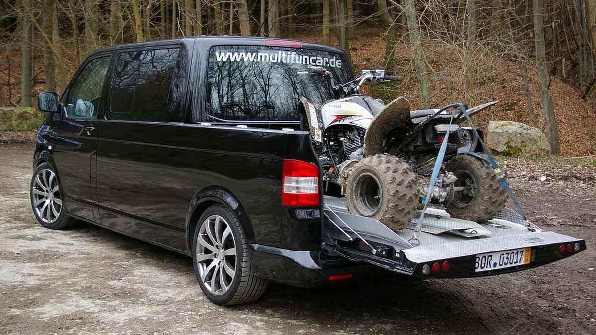 Ein schwarzer Lieferwagen mit einem Geländefahrzeug auf der Ladefläche.