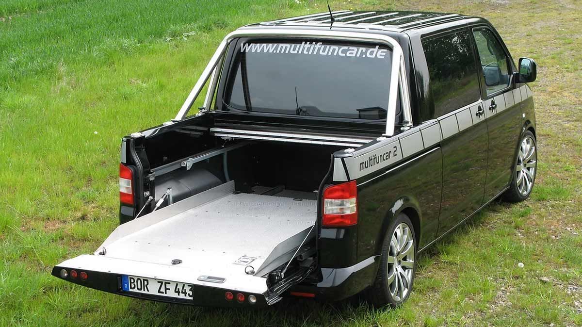 Ein schwarzer Lieferwagen mit offener Hintertür ist auf einer Wiese geparkt.