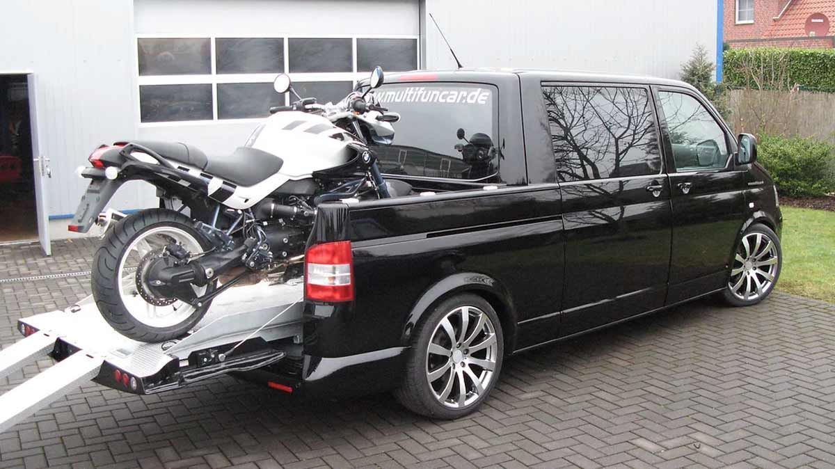 Ein schwarzer Lieferwagen zieht ein Motorrad auf einem Anhänger.