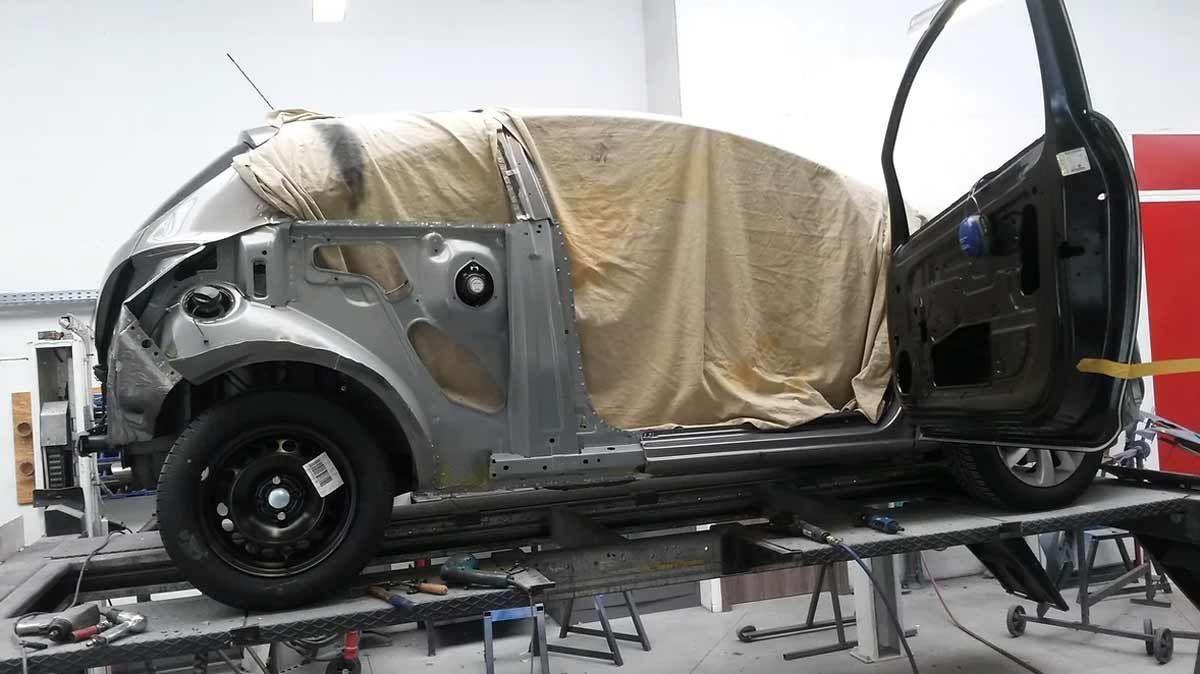 In einer Garage wird bei geöffneter Tür an einem Auto gearbeitet