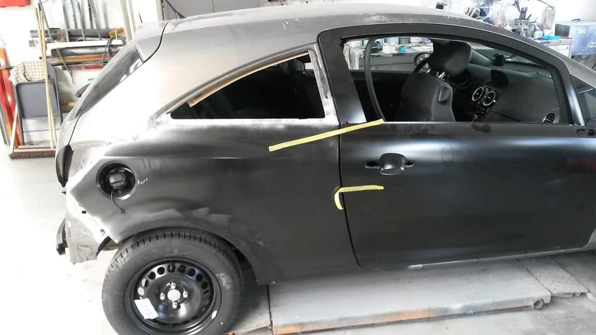Ein schwarzes Auto steht auf einer Hebebühne in einer Garage.