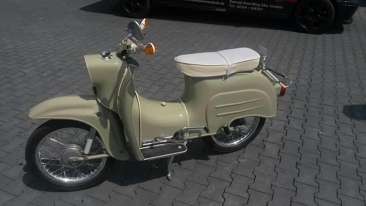 Ein Roller ist auf einem Ziegelsteinpflaster neben einem Auto geparkt