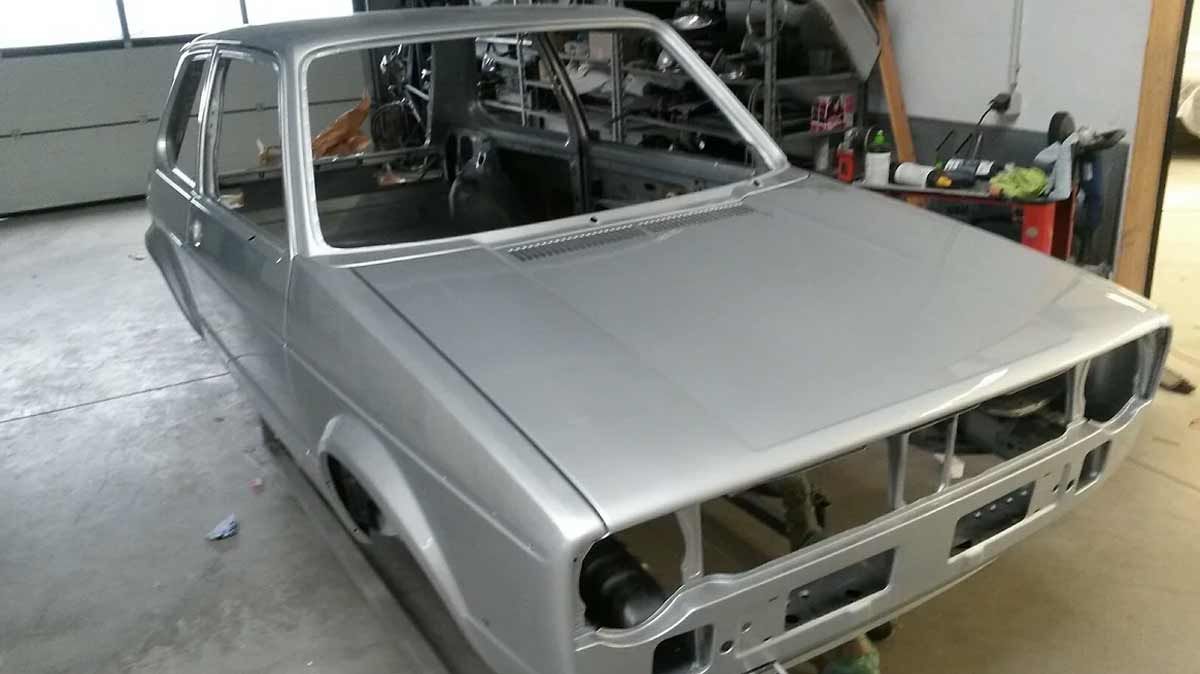 Ein silbernes Auto steht ohne Verdeck in einer Garage.