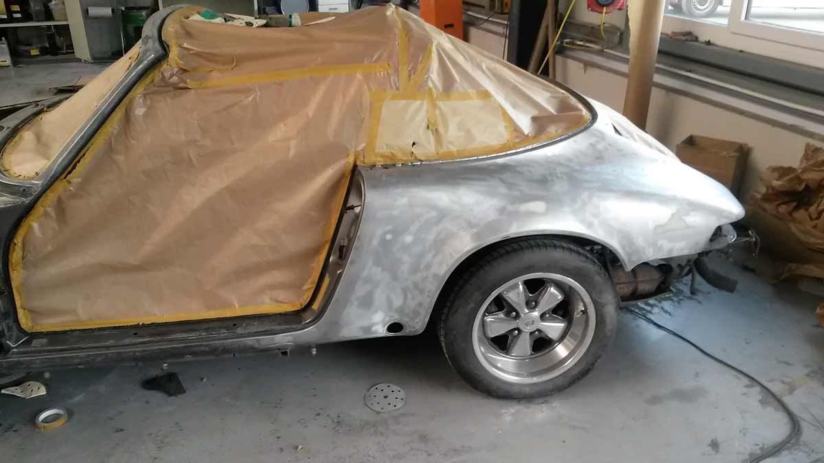 Ein silbernes Auto wird in einer Garage lackiert.