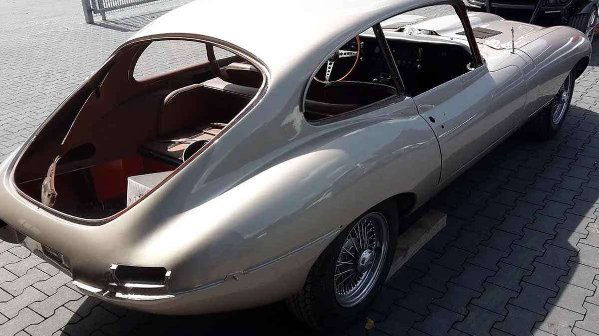 Ein silbernes Auto mit offenem Kofferraum steht auf einem Bürgersteig