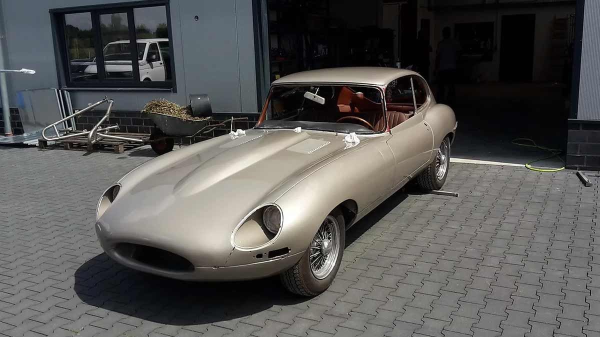 Ein goldenes Auto ist auf einer gepflasterten Auffahrt vor einer Garage geparkt.