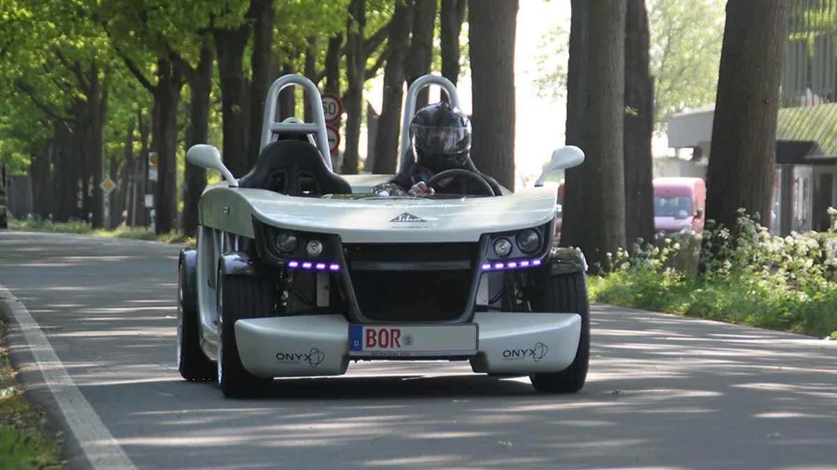 Ein Mann fährt einen Sportwagen eine Straße entlang.