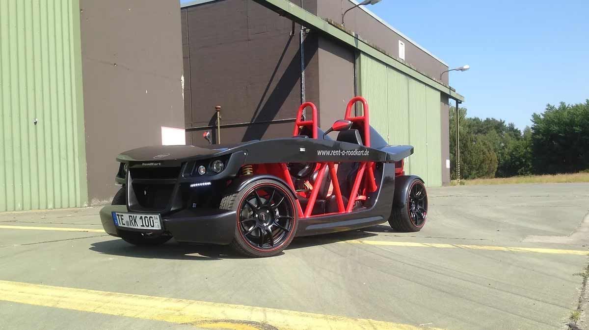 Ein schwarz-rotes Auto steht auf einem Parkplatz vor einem Gebäude.