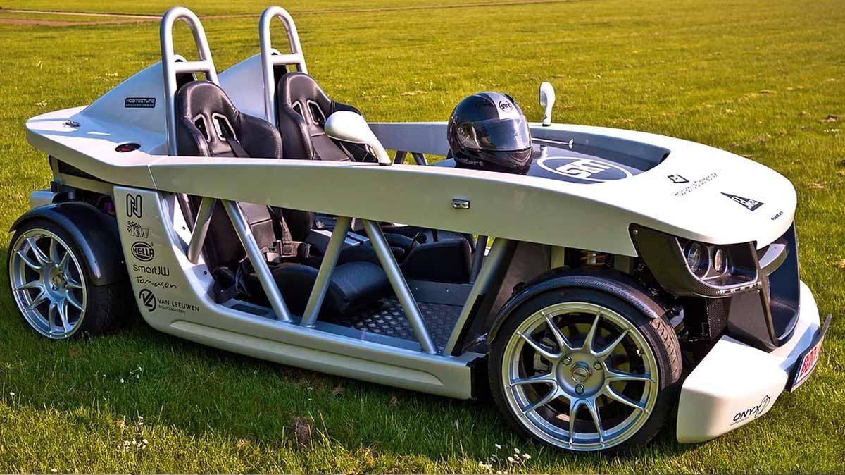 Ein weißer Sportwagen mit einem Helm auf dem Fahrersitz ist im Gras geparkt.