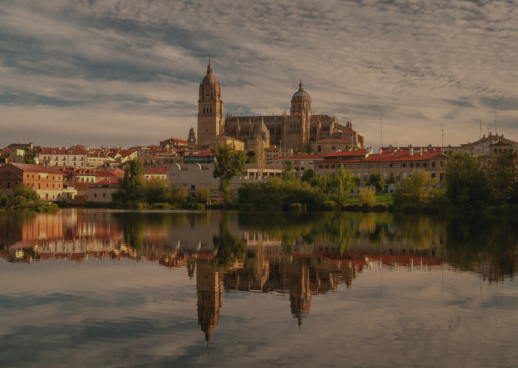 A large building is reflected in a lake in front of a city.
