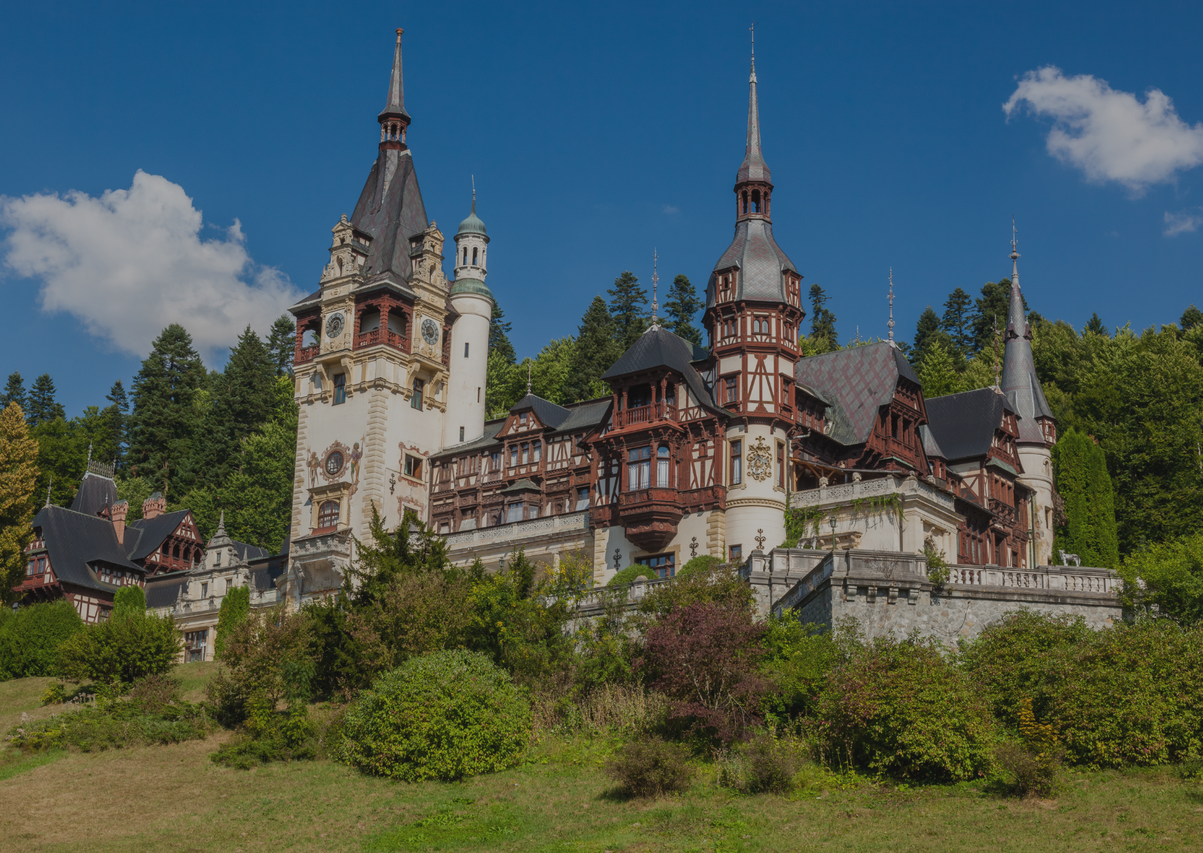 A large castle is sitting on top of a hill surrounded by trees.